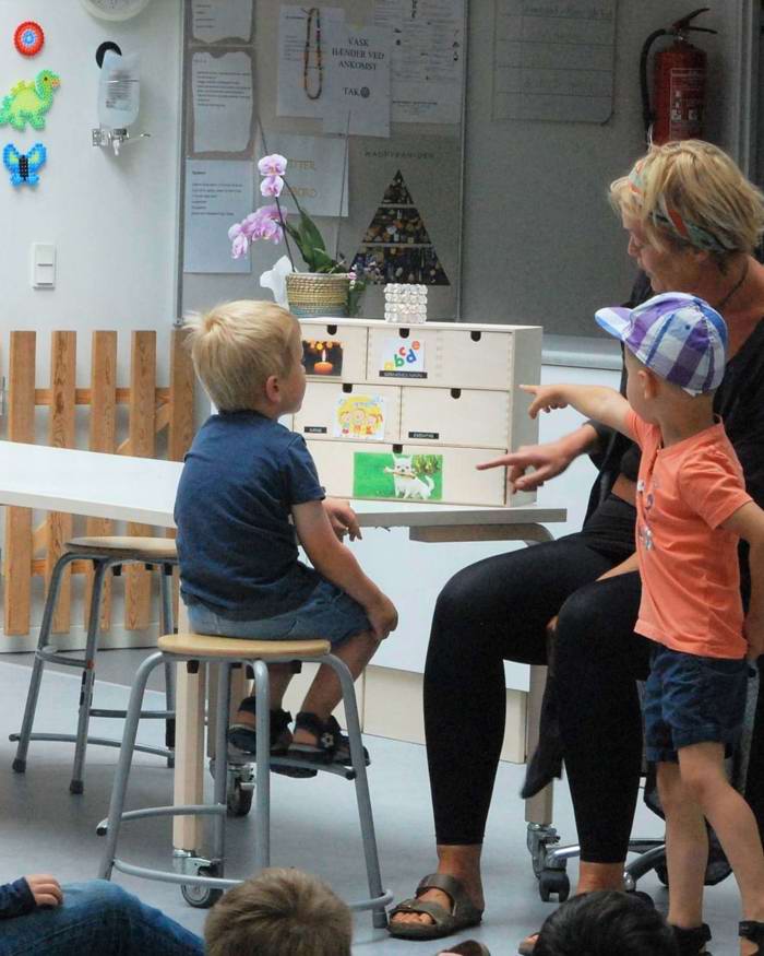 Børn og pædagog peger på skuffer